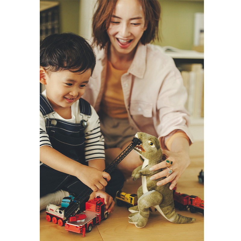 指にブシュロンの色石リングを重ね付けして男の子とおもちゃで遊ぶママ