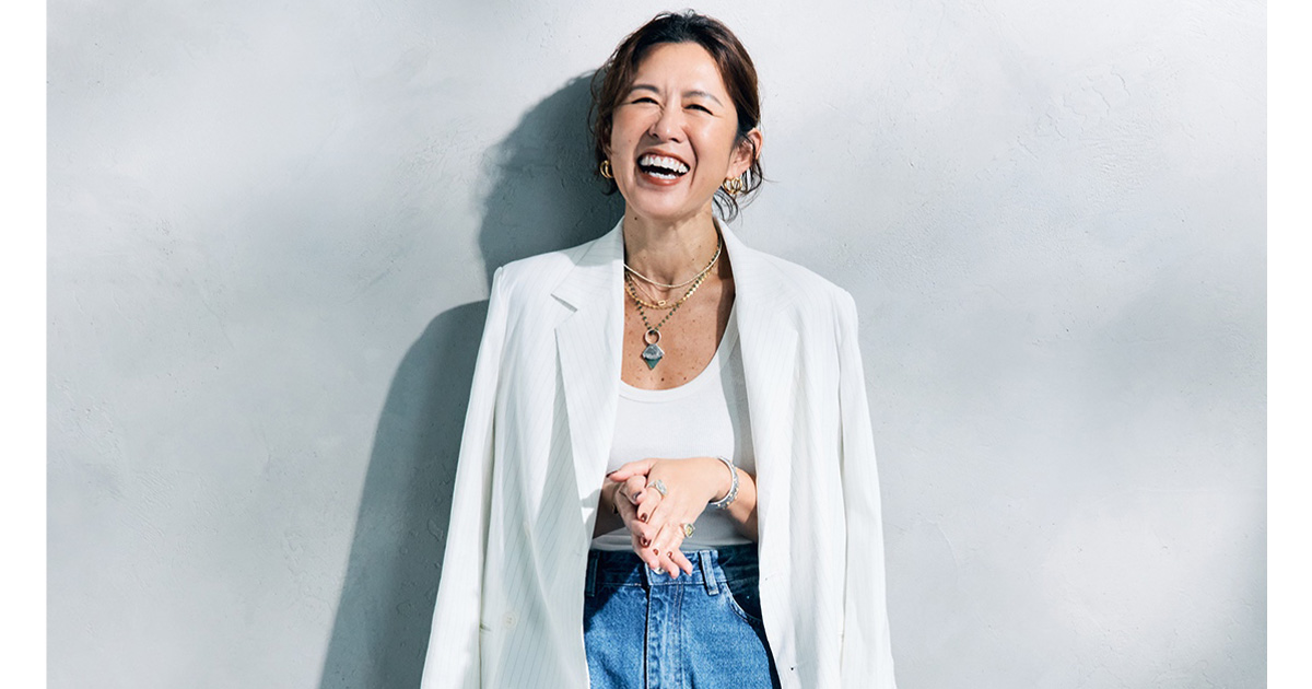 白のタンクトップとデニムに白のジャケットを肩掛けした大草直子さん
