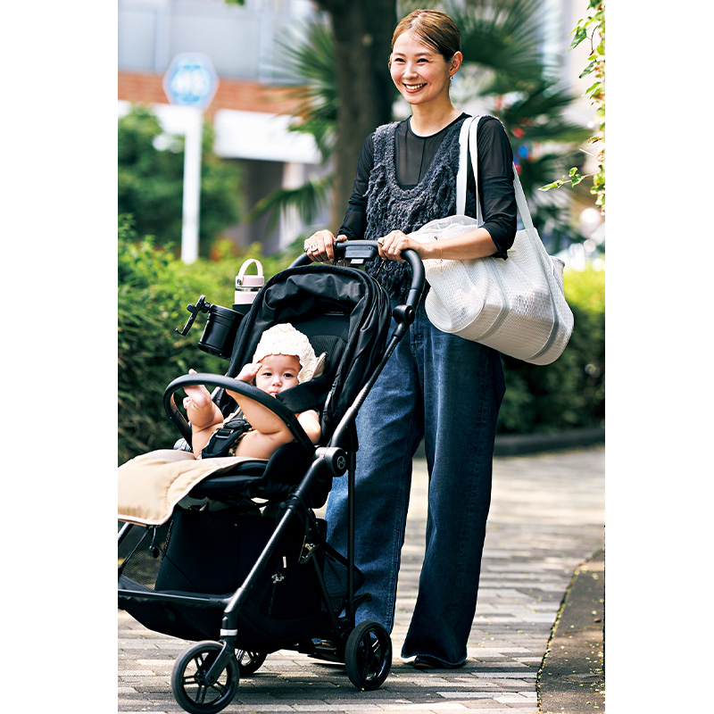トートバッグを肩にかけてベビーカーをひくママ