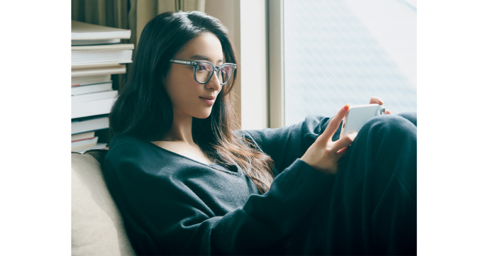 ソファーでスマホを見るメガネ姿の武井咲さん