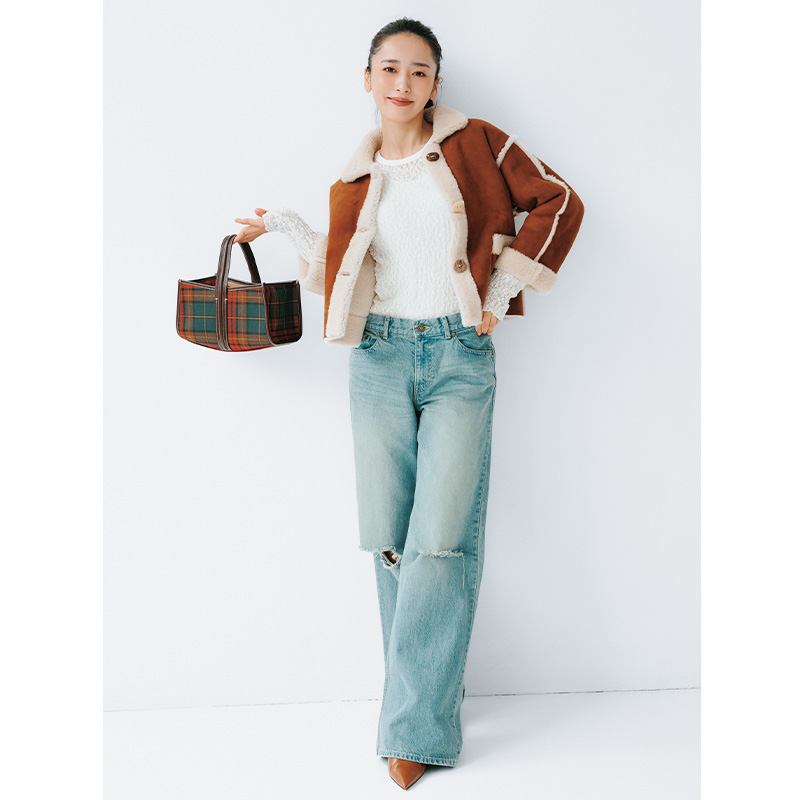 レーストップスとデニムにムートンジャケットを羽織ってチェック柄のバッグを持つ近藤千尋さん
