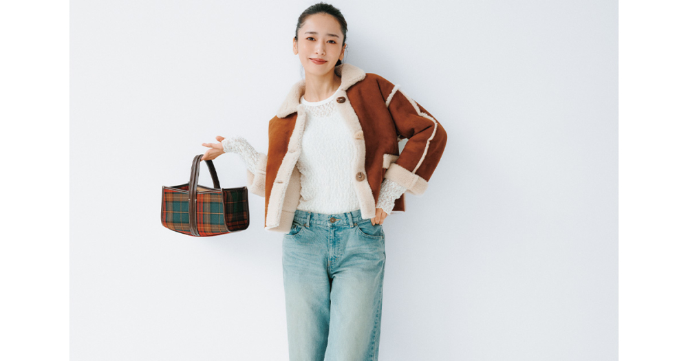 レーストップスとデニムにムートンジャケットを羽織ってチェック柄のバッグを持つ近藤千尋さん