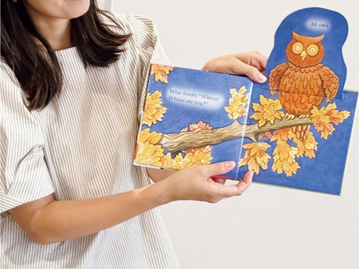 ふくろうが描かれた絵本を手に持つ郡司あゆみさん