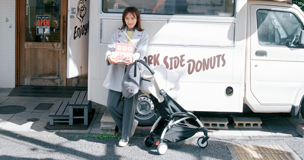 夏菜さんがテイクアウトのドーナツの箱を持って店前にたたずむ様子