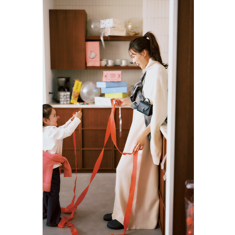 イロットのケープシルエットのニットワンピにチェックシャツやミニバッグを斜めがけしたホムパコーデ