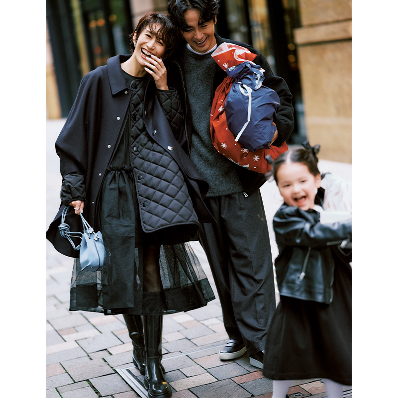 シーニュのチュールワンピースにキルティングコートとポンチョコートを重ね着してロングブーツを履いたママと荷物を持つパパと子ども