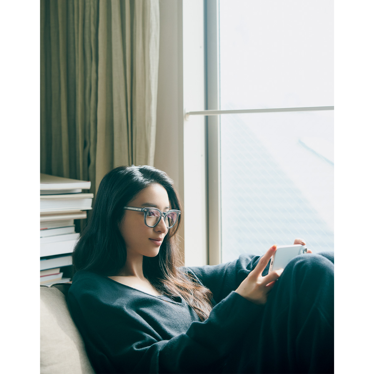 ソファーでスマホを見るメガネ姿の武井咲さん