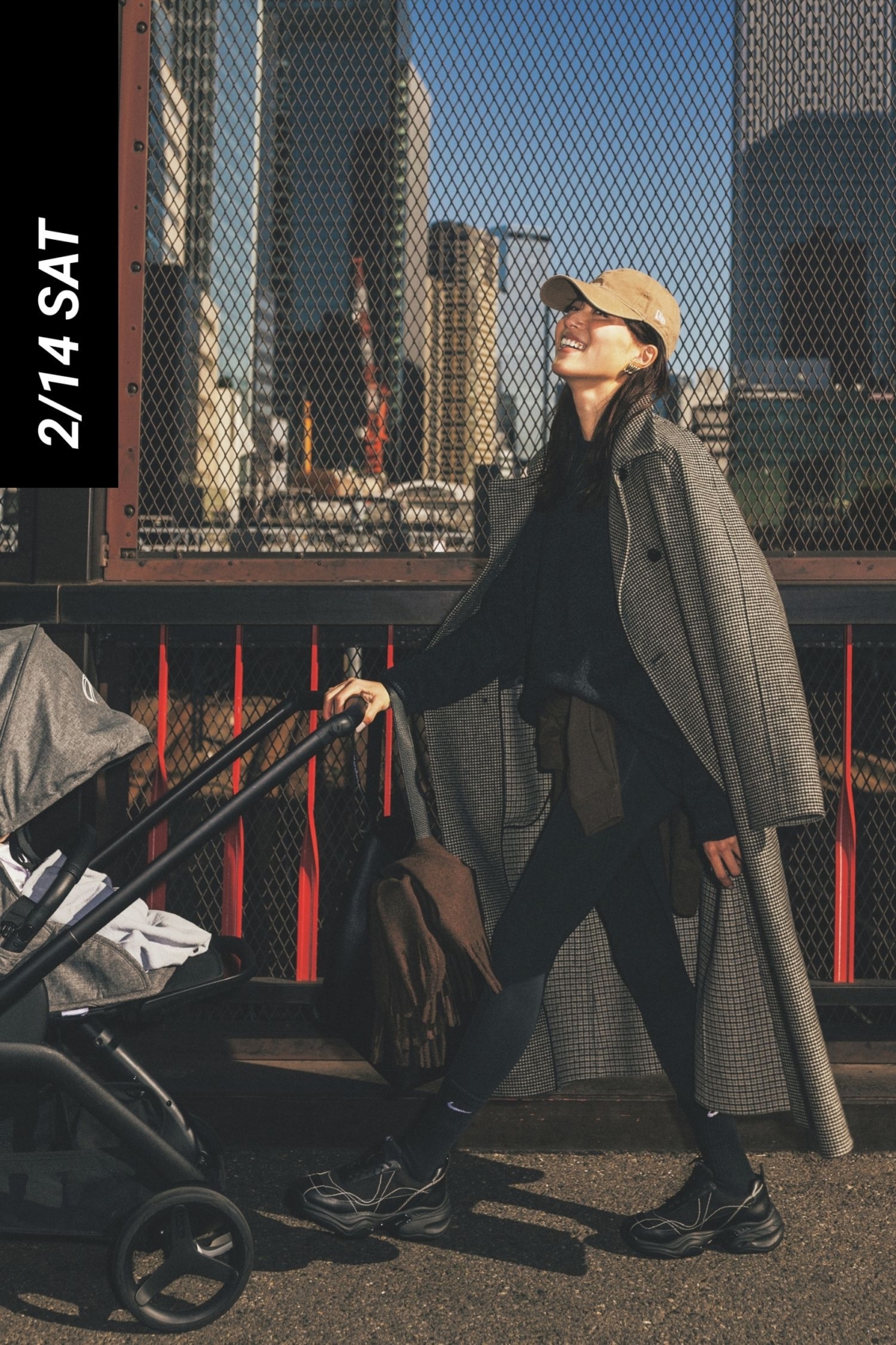 ニットからレギンスやスニーカーまで黒でまとめたコーデにチェック柄のロングコートを羽織ってベージュのキャップを被ったベビーカーママ