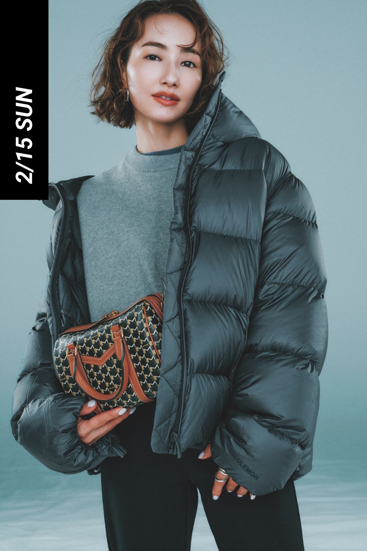 グレーニットと黒パンツにダウンを羽織って柄バッグを持った辻元舞さん