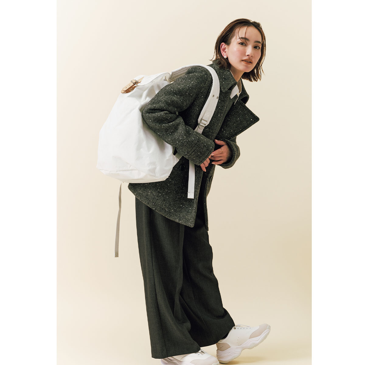 柄入りコートとスラックスに白の大きめリュックとOAOの白スニーカーを合わせたコーデ