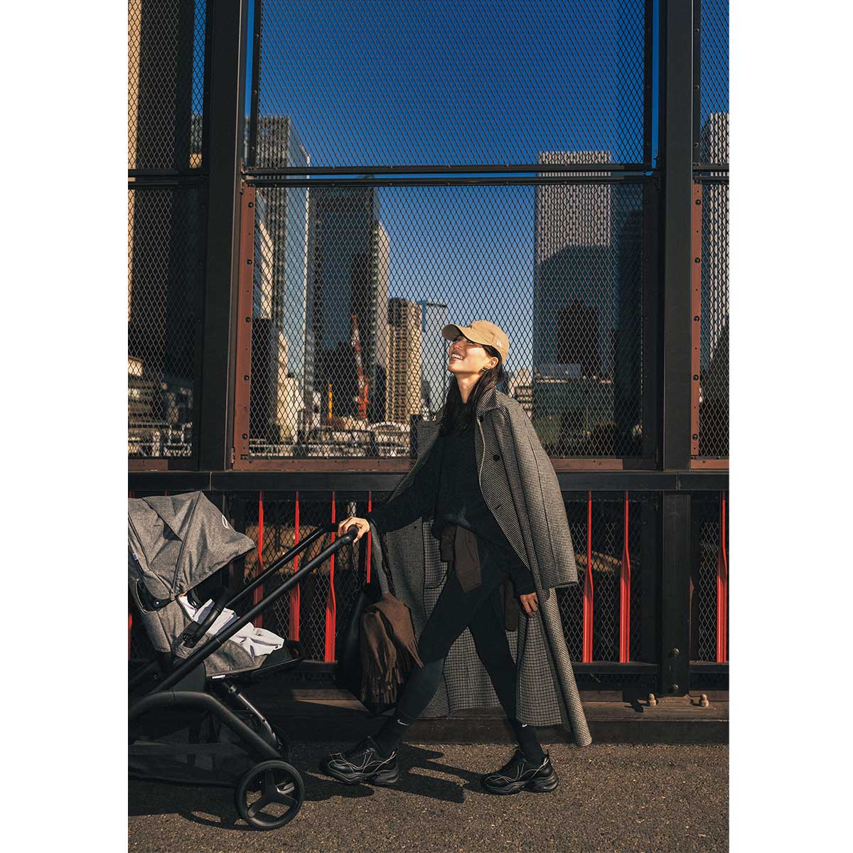 ベビーカーを引いているレギンス×コートスタイルのママ