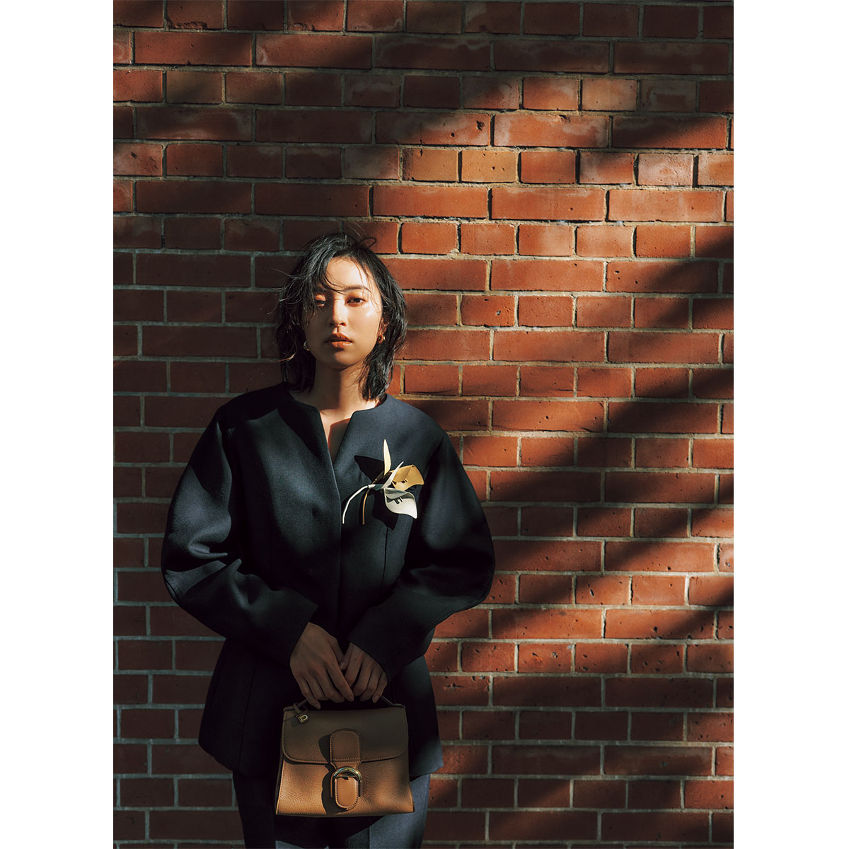 ネイビーのジャケットの胸元にSANTÉ BY ETRÉTOKYOのレザーコサージュをつけたセレモニーコーデ