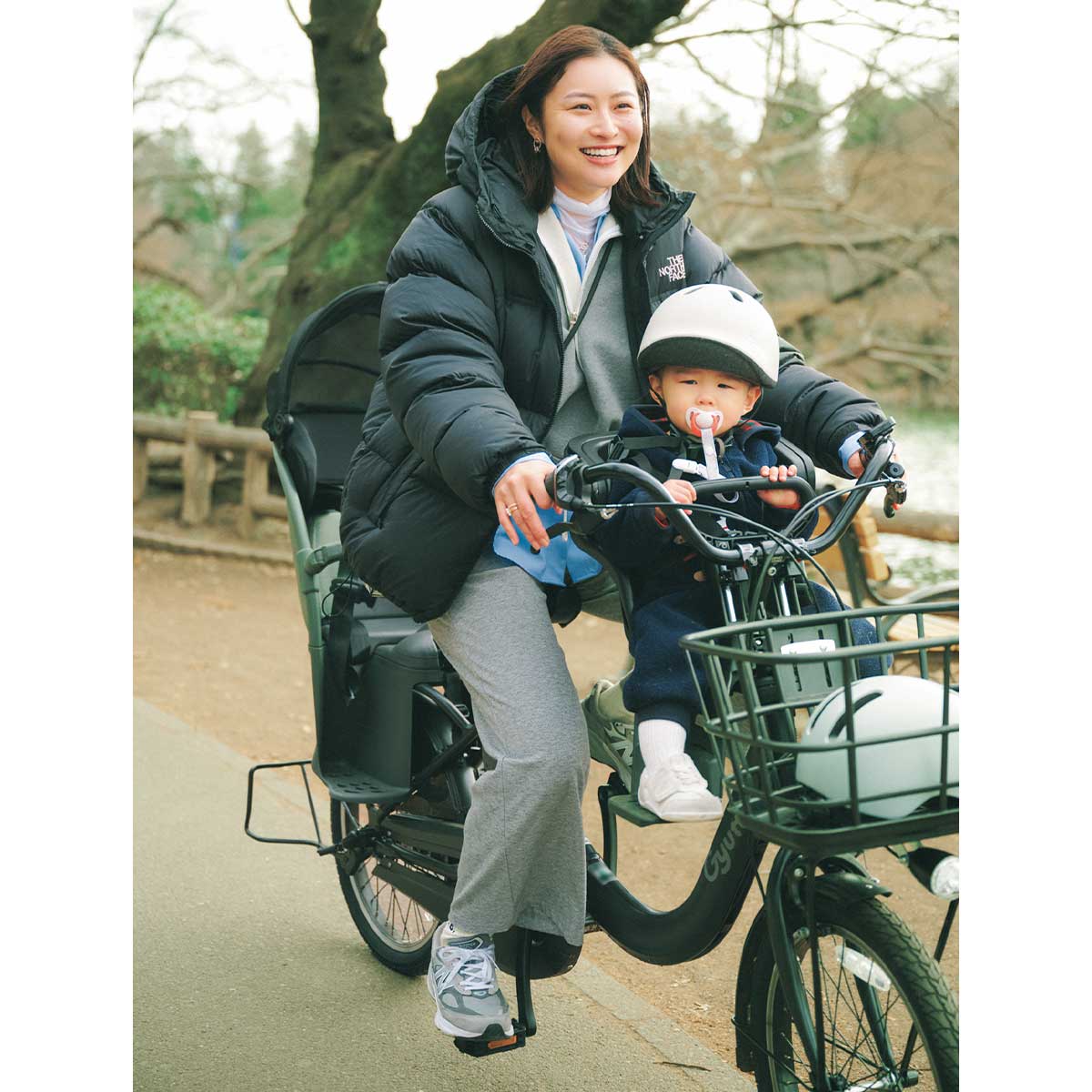 子どもを乗せて自転車で走るオシャレママ