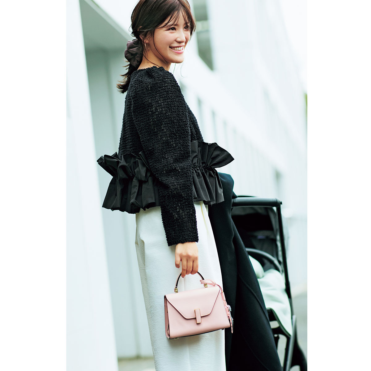 黒の甘ブラウスと白のワイドパンツにピンクのバッグを持った子連れママ