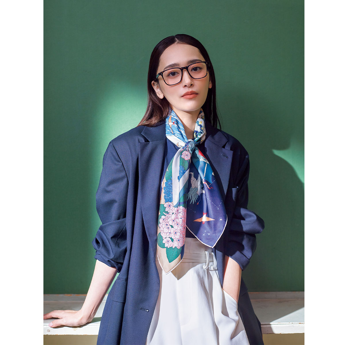 ネイビーのジャケットの首元にエルメスのブルーベースの柄スカーフを巻いたセレモニーコーデ