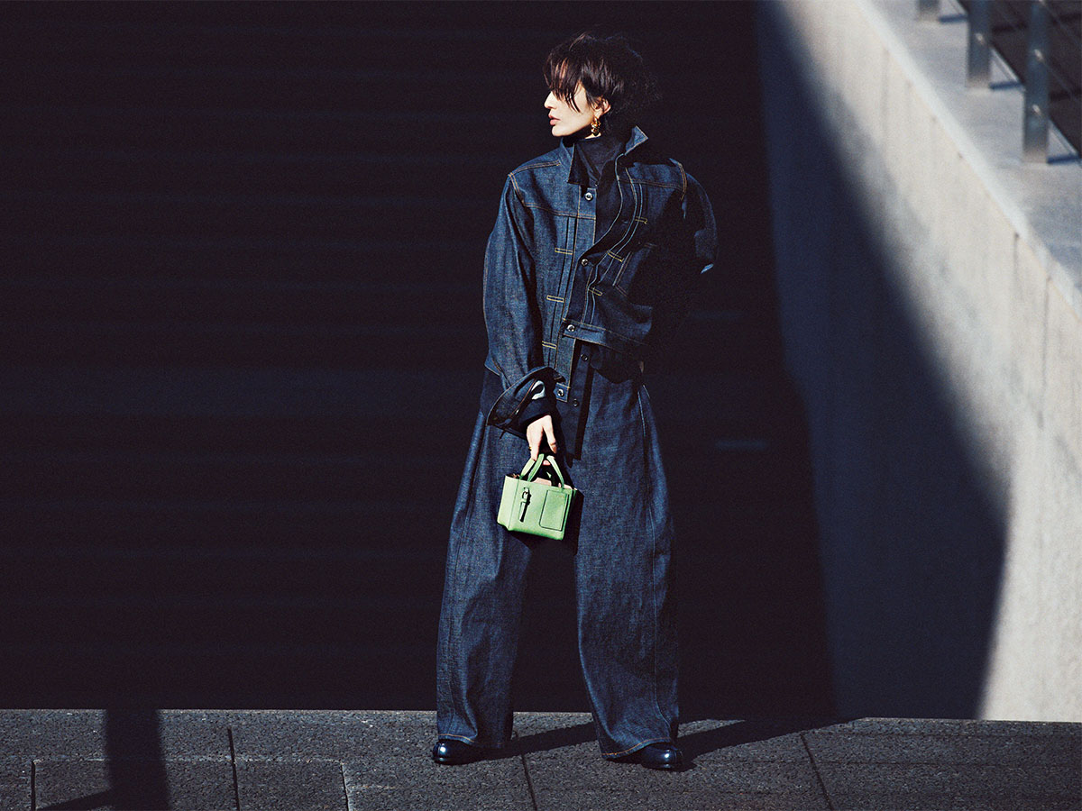 デニムオンデニムのインナーにネイビータートルをなじませてグリーンのミニバッグを持ったスタイル
