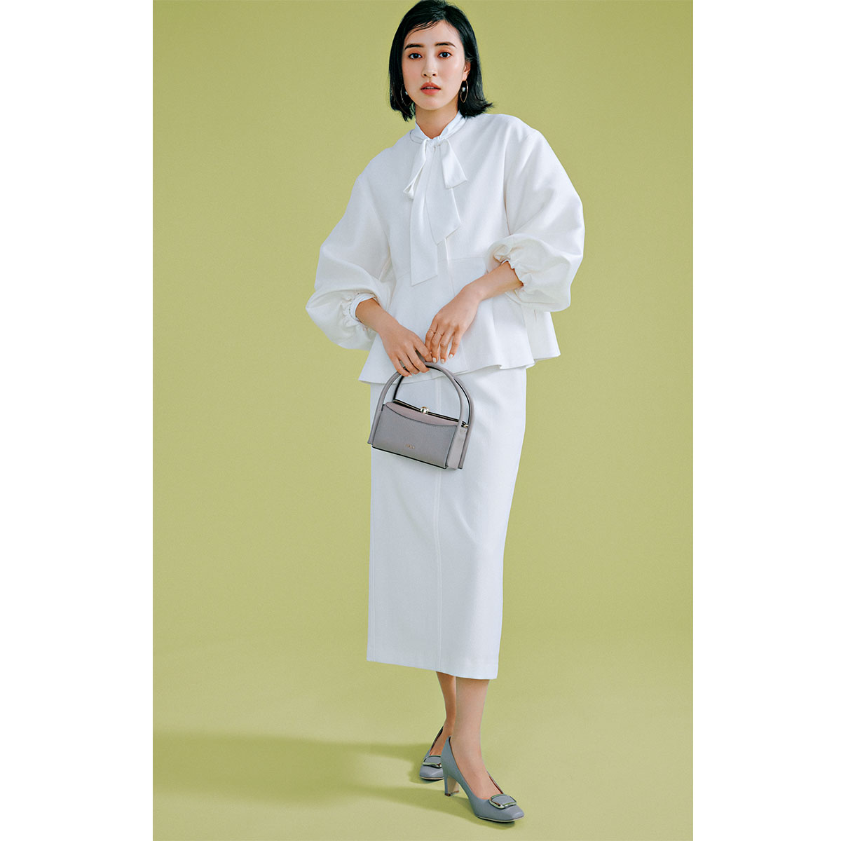 グリーンレーベルのホワイトのボリューム袖ジャケットとボウタイブラウスとタイトスカートを着た岡本あずささん