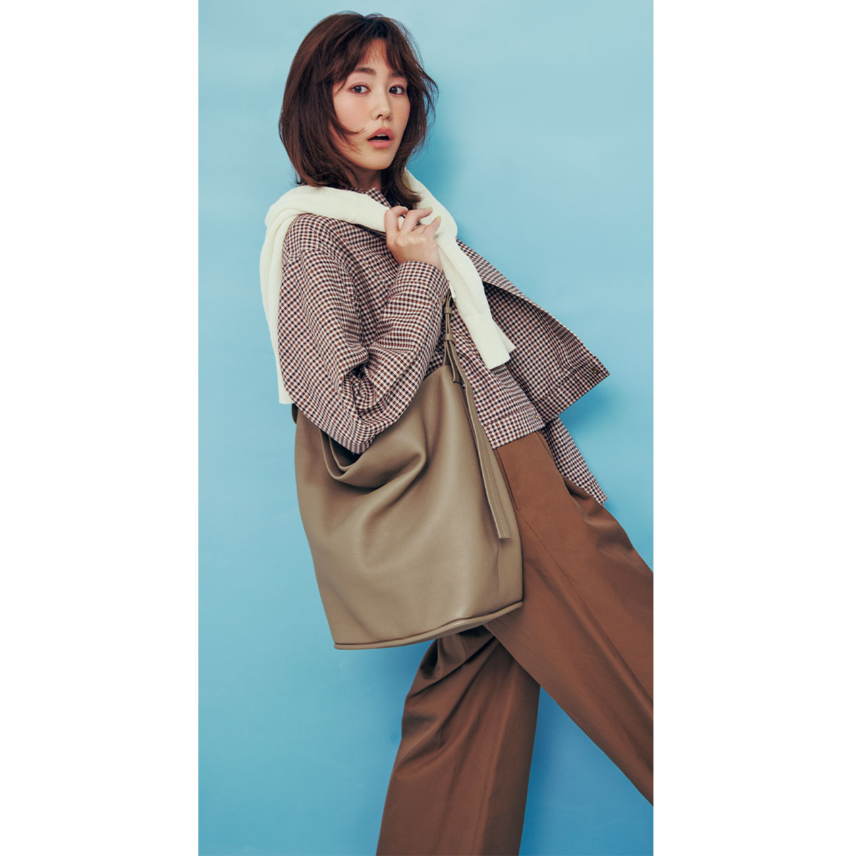 チェック柄のブルゾンと茶色のパンツコーデにバケツ型ショルダーバッグを肩にかけた桐谷美玲さん
