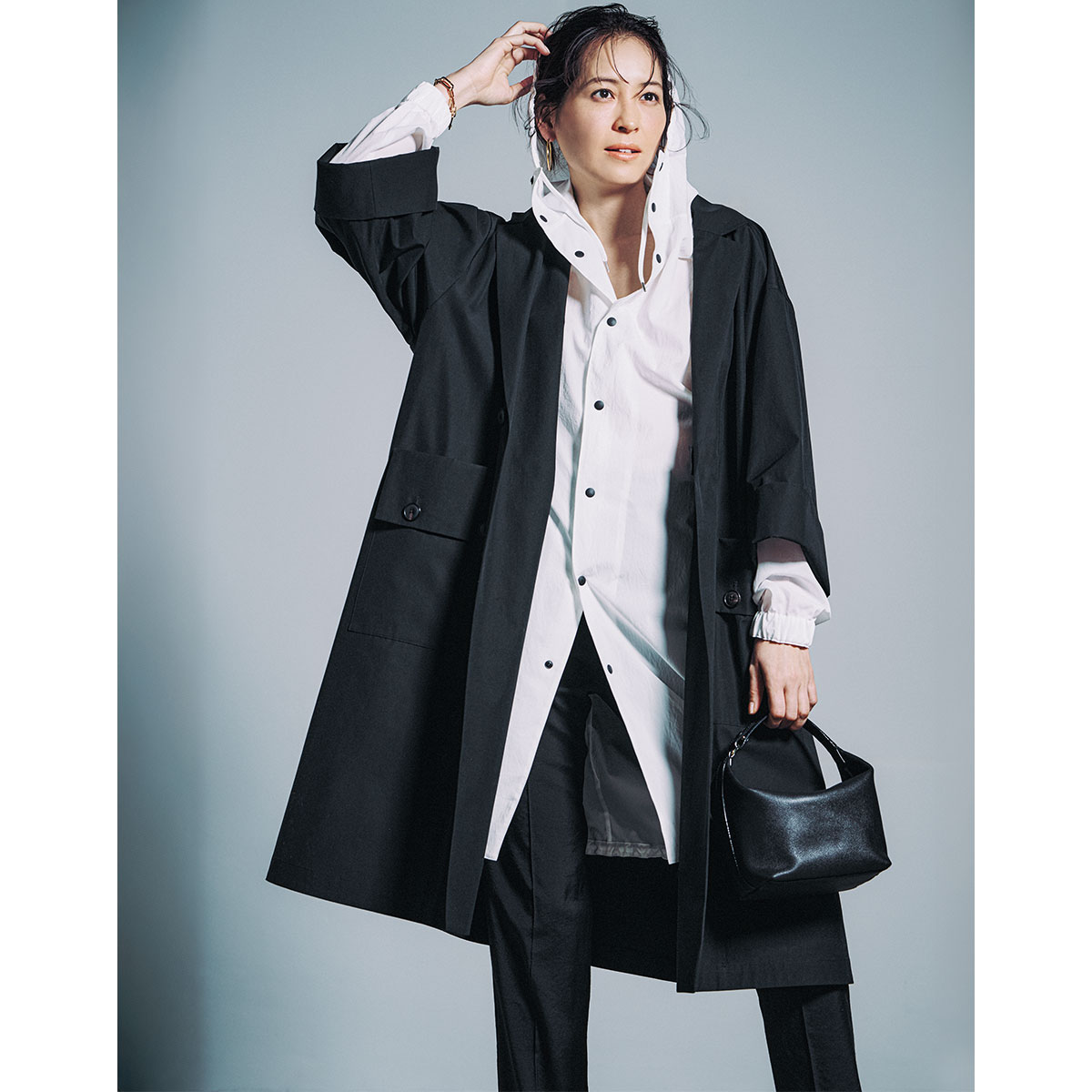 白のフードアウターの上にゆったりとしたオーバーサイズの黒コートを羽織ったレイヤードコーデ