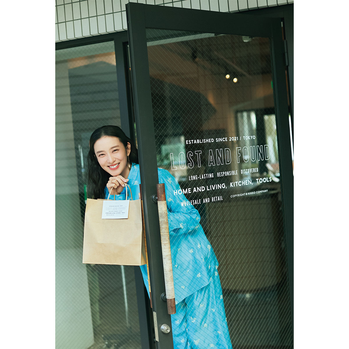 LOST AND FOUND TOKYO STOREの入口で紙袋持つ武井咲さん