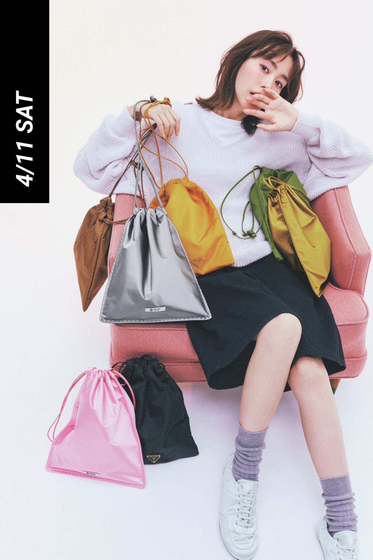 ニットとデニムのハーフパンツコーデに色とりどりのプラダの巾着型ポーチバッグを持った桐谷美玲さん