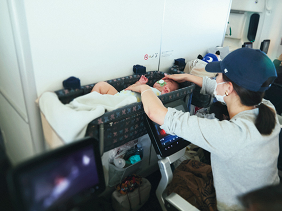 飛行機の機内で子どもをバシネットに寝かせる咲和希さん