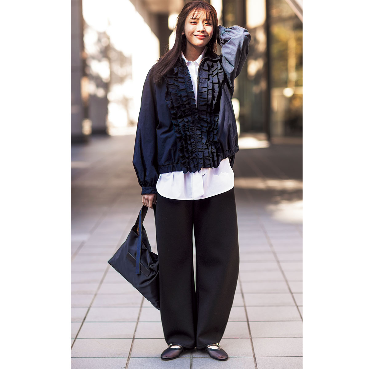 白シャツと黒パンツに前面にたっぷりフリルがついたブルゾンを羽織ったコーデ