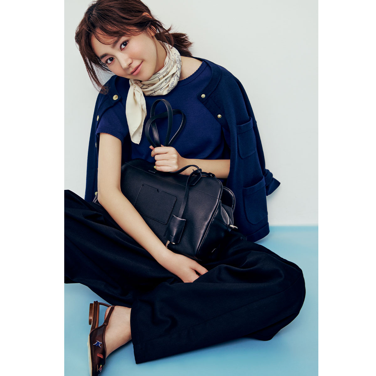カーディガンとパンツにスカーフを巻いたキレイめコーデにOSOIのアローズ別注の黒バッグを抱えた桐谷美玲さん