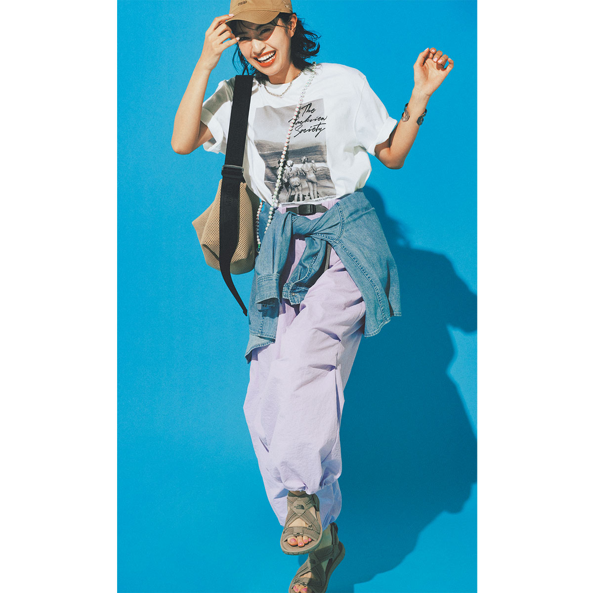 プリントTシャツとパープルの撥水カーゴパンツにデニムシャツを腰に巻いてアクティブにまとめた着こなし