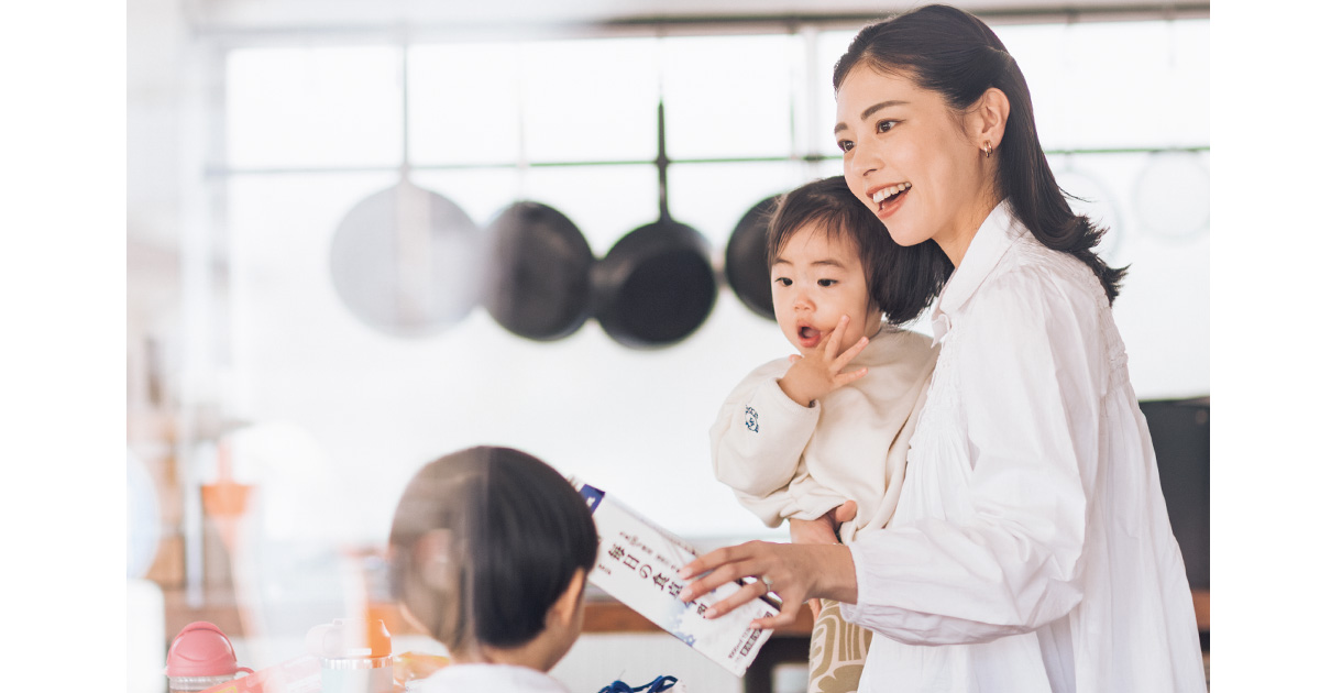 子どもを抱っこしながら牛乳を注ぐママ