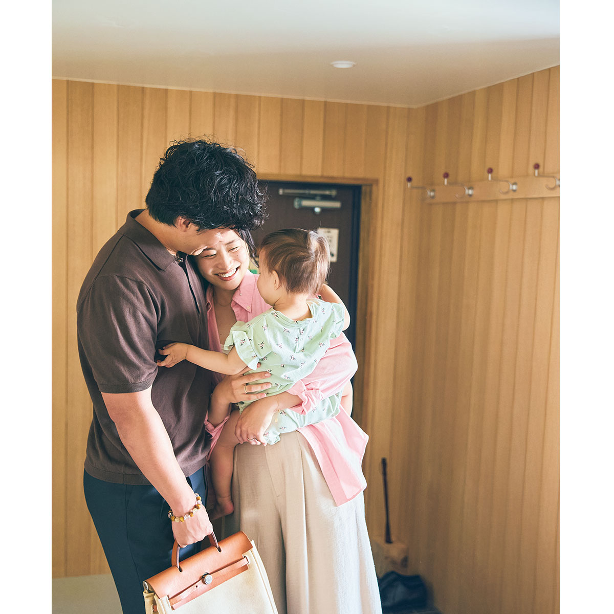 玄関でハグするご夫婦と1歳の娘さん