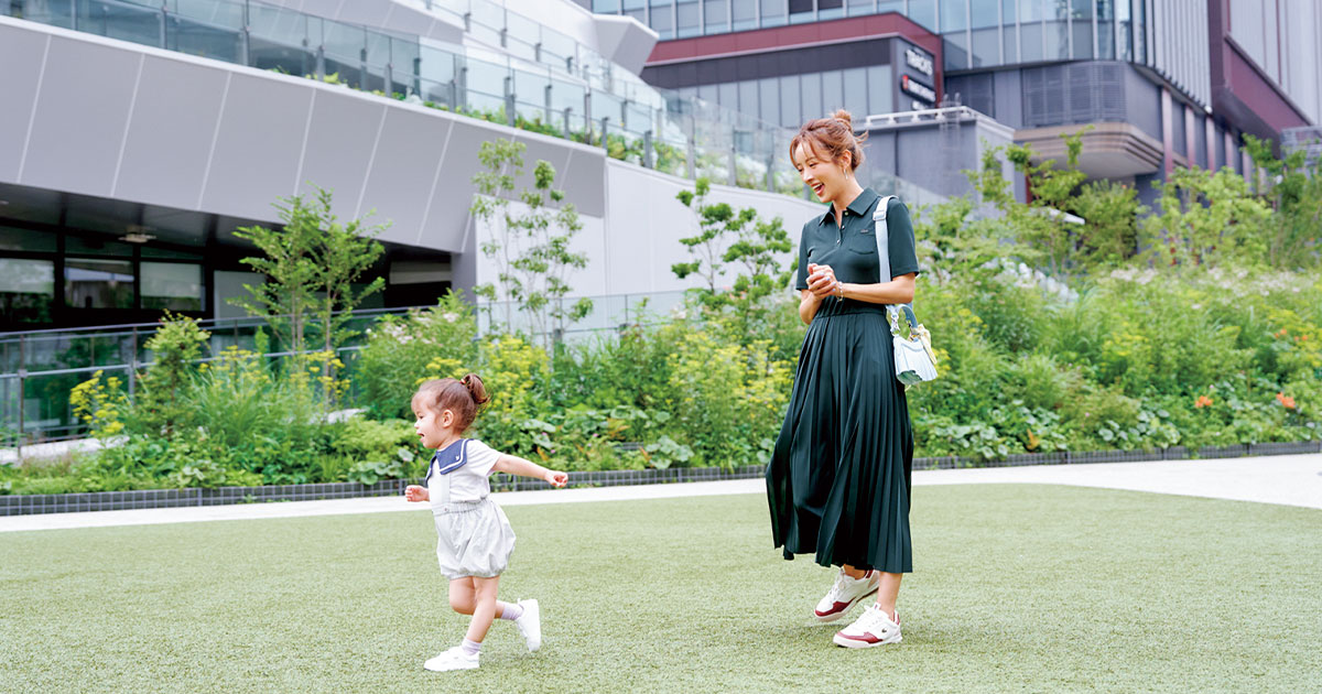 芝生の上を走る子どもと見守る夏菜さん