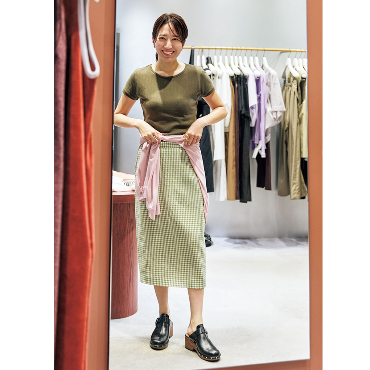 6（ROKU）SHINJUKUでTシャツとスカートに腰にシャツを巻いたコーデを試着するVERYライターの桃井真由さん