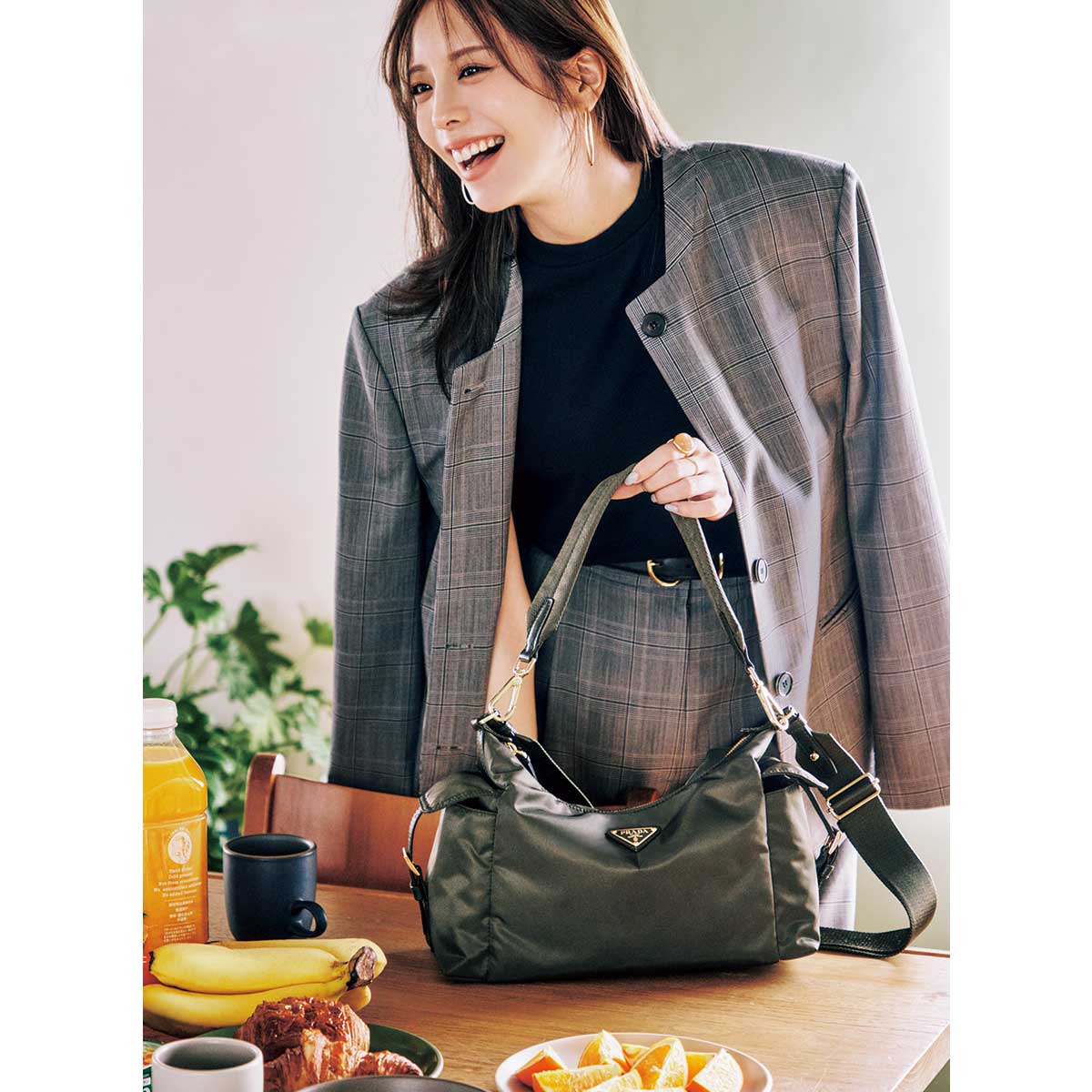 プラダのRe-Nylonの黒バッグをテーブルに置くジャケットを着た女性