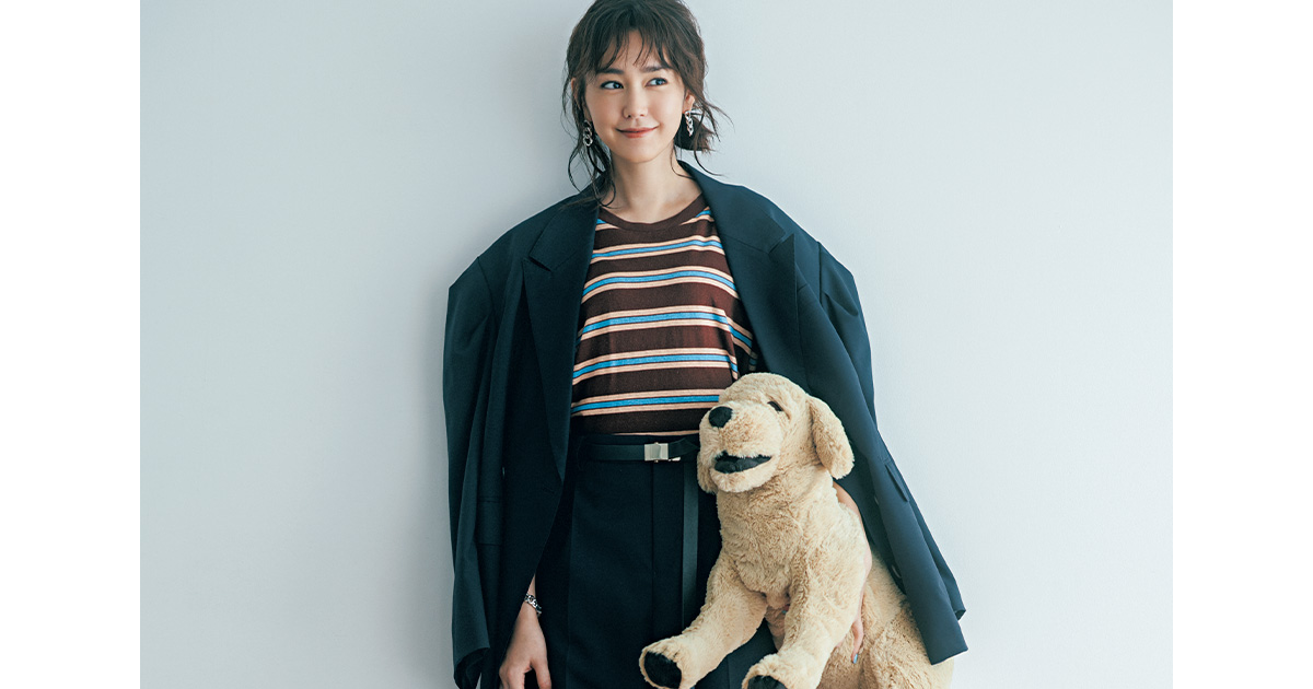 マルチボーダートップスとパンツにジャケットを肩掛けして犬のぬいぐるみを持った桐谷美玲さん